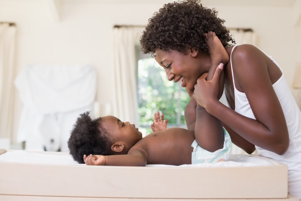 Happy mother with baby girl on changing table