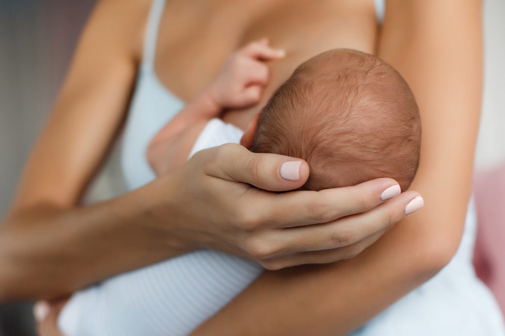 Young mother, sitting in the bedroom with her newborn son