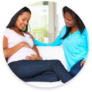 Pregnant woman and her friend sitting on the couch