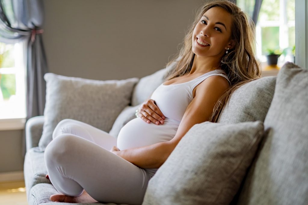 Young female holding her stomach, sitting on a lounge