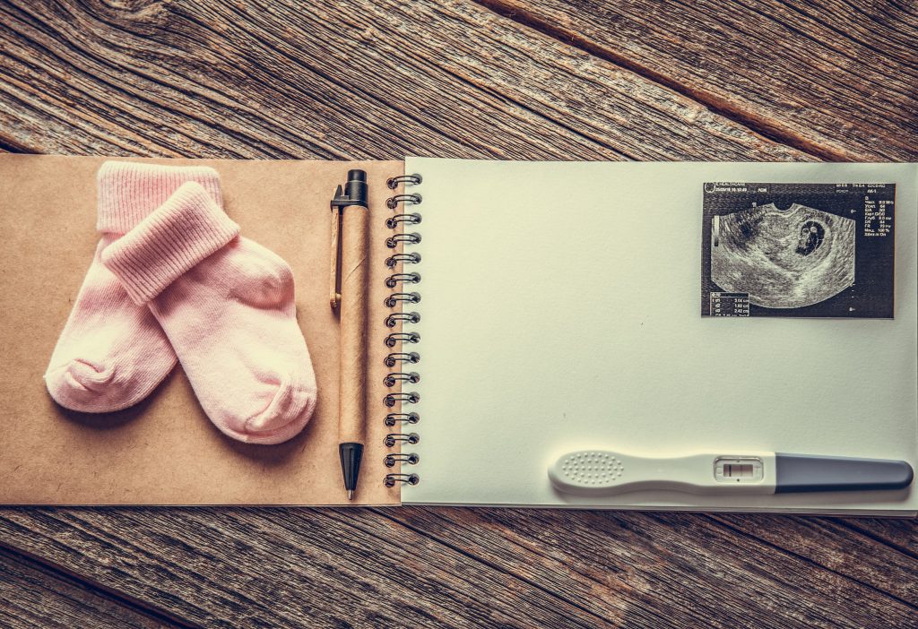 An album with baby socks, a pen, pregnancy test and scan