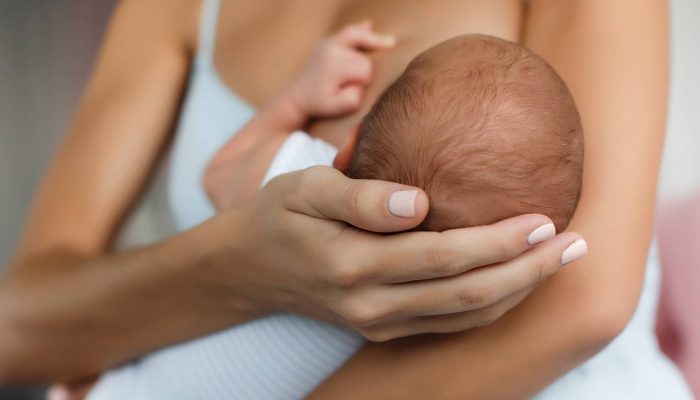 Young mother, sitting in the bedroom with her newborn son Young mother, sitting in the bedroom with her newborn son
