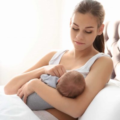 Young mother breastfeeding baby in bed